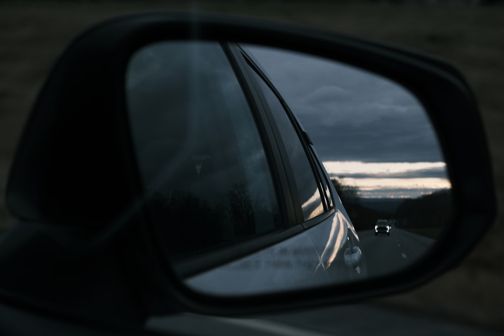 a car's side view mirror with a dark sky in the background