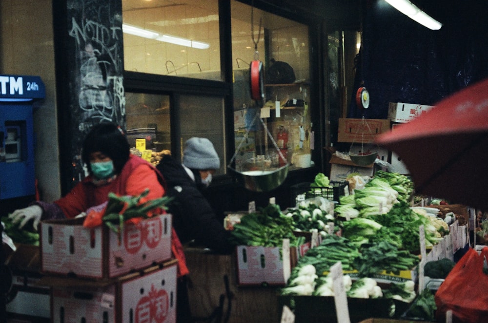 Eine Frau mit Gesichtsmaske steht vor einem Gemüsestand