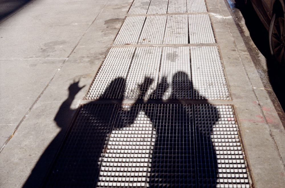 a shadow of two people standing on a sidewalk