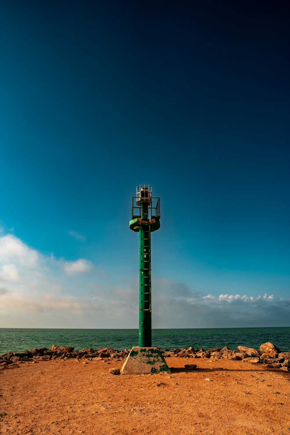 a green light pole sitting on top of a sandy beach