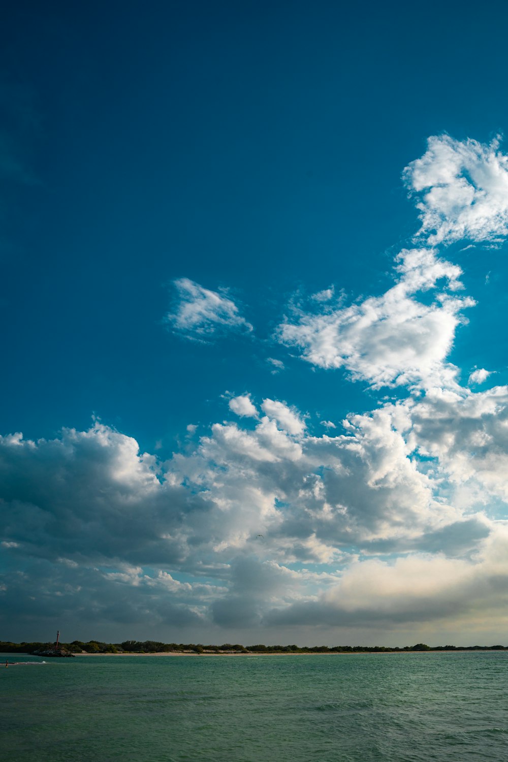 a large body of water under a cloudy blue sky