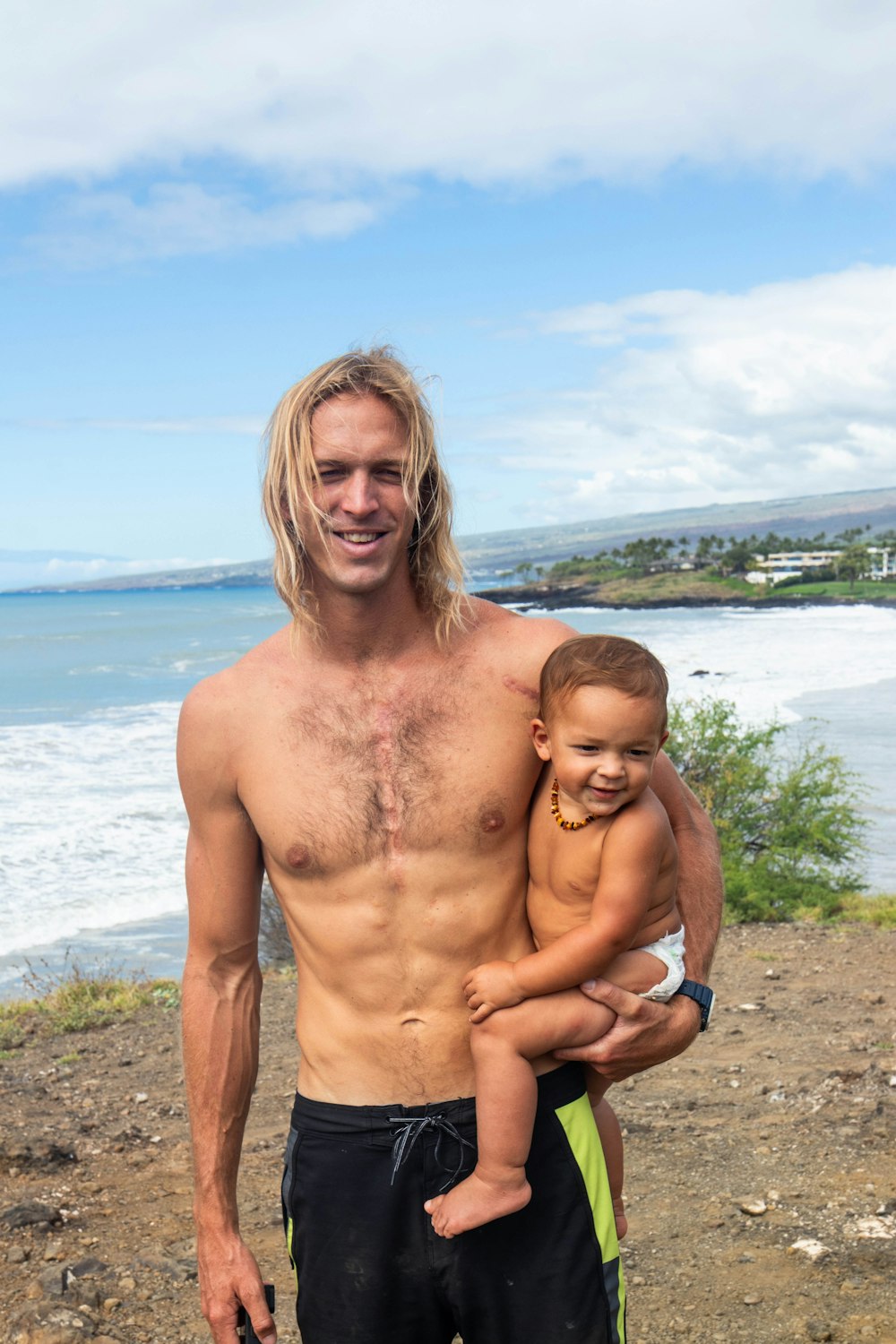 a man holding a small child on top of a beach