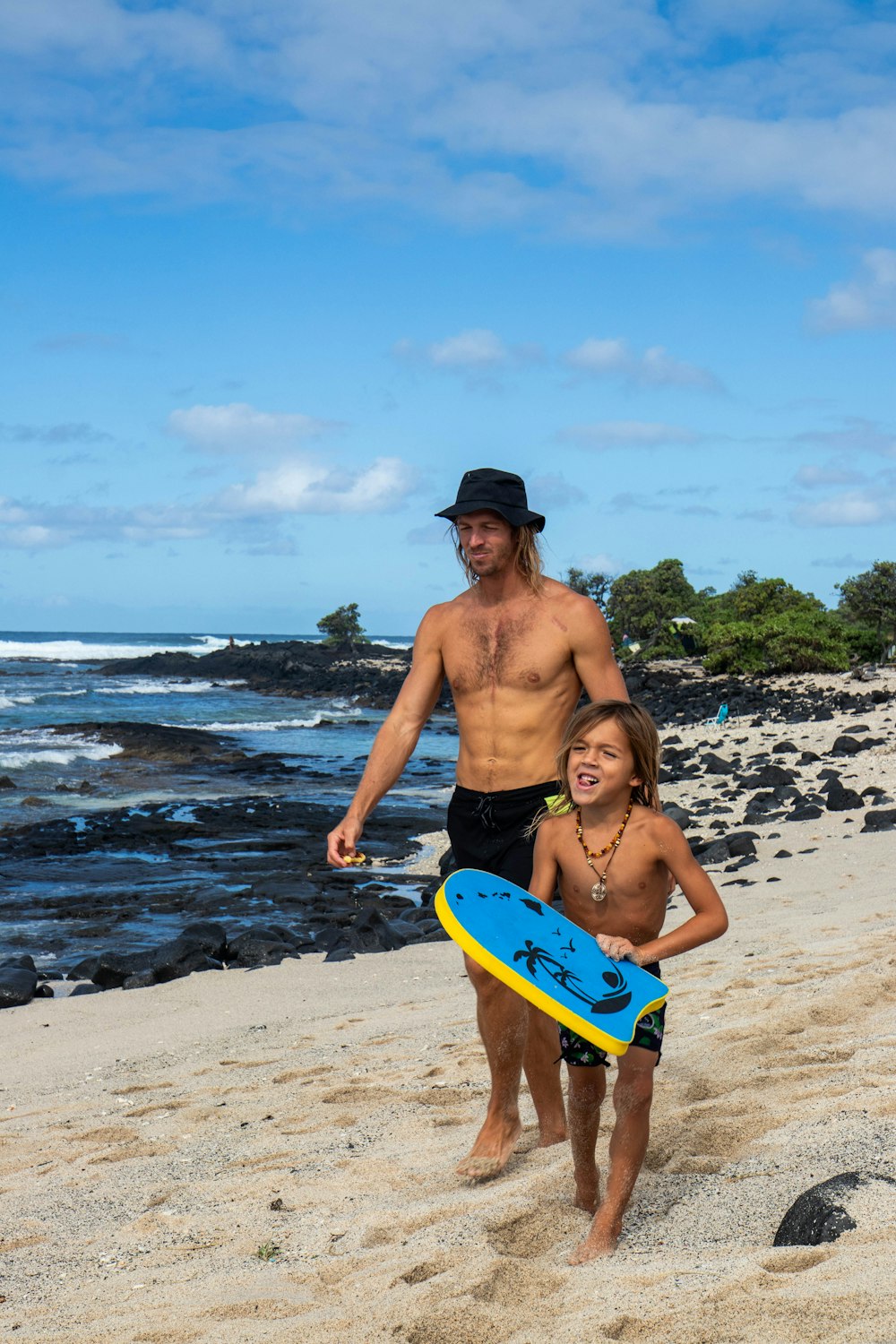 a man and a little girl walking on a beach