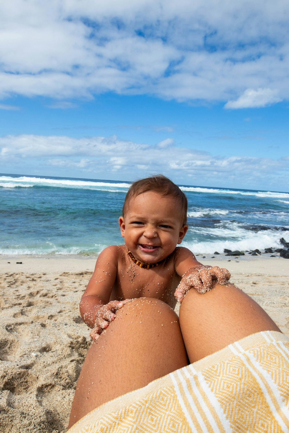 해변의 모래 위에 앉아있는 아기