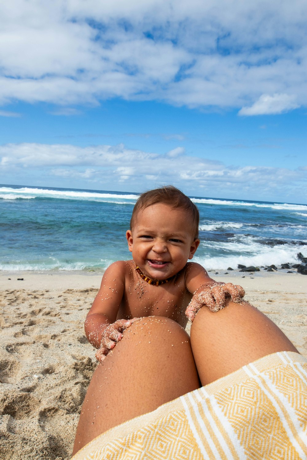 a baby sitting in the sand on the beach