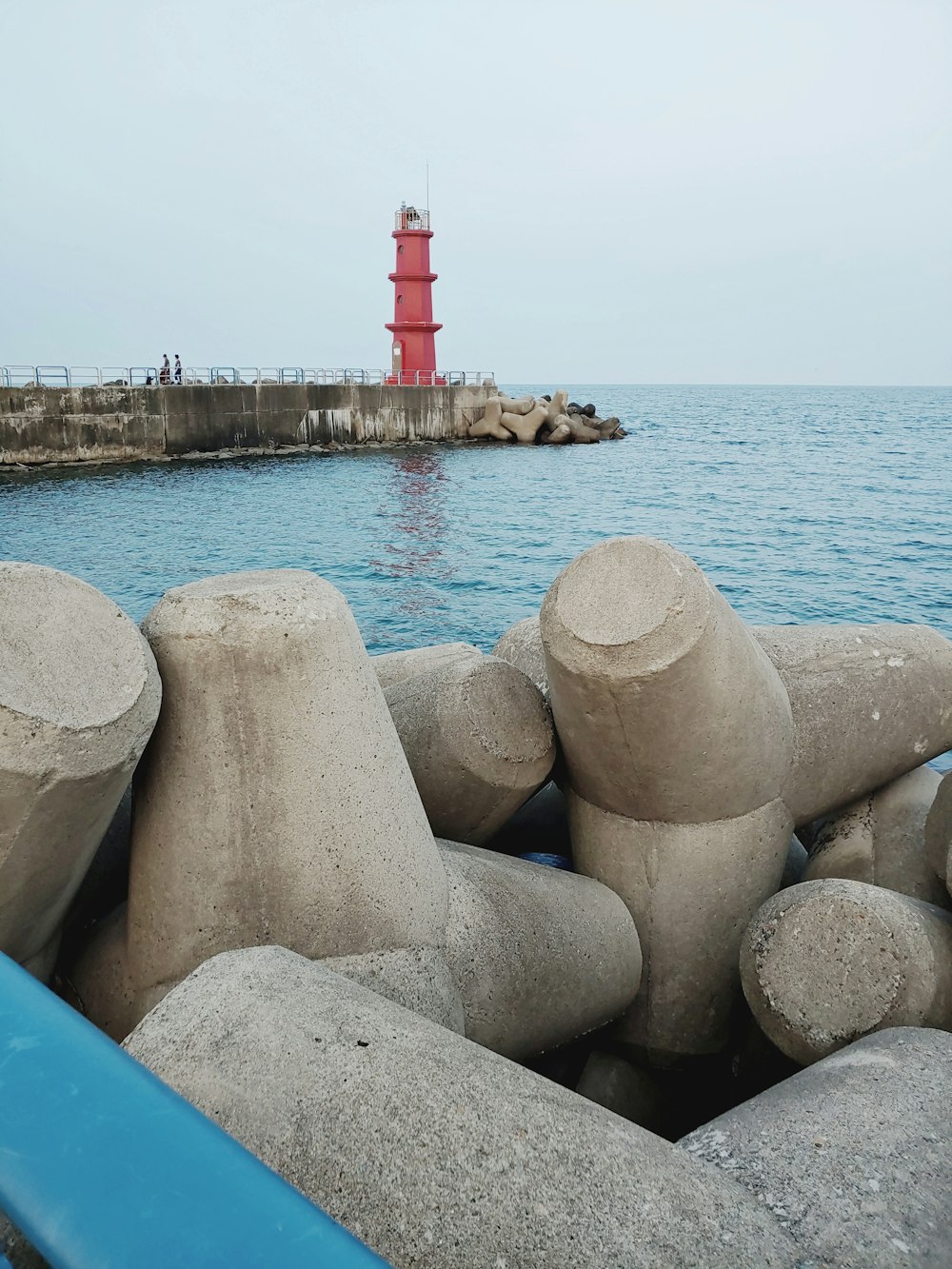 a red light house sitting on top of a body of water