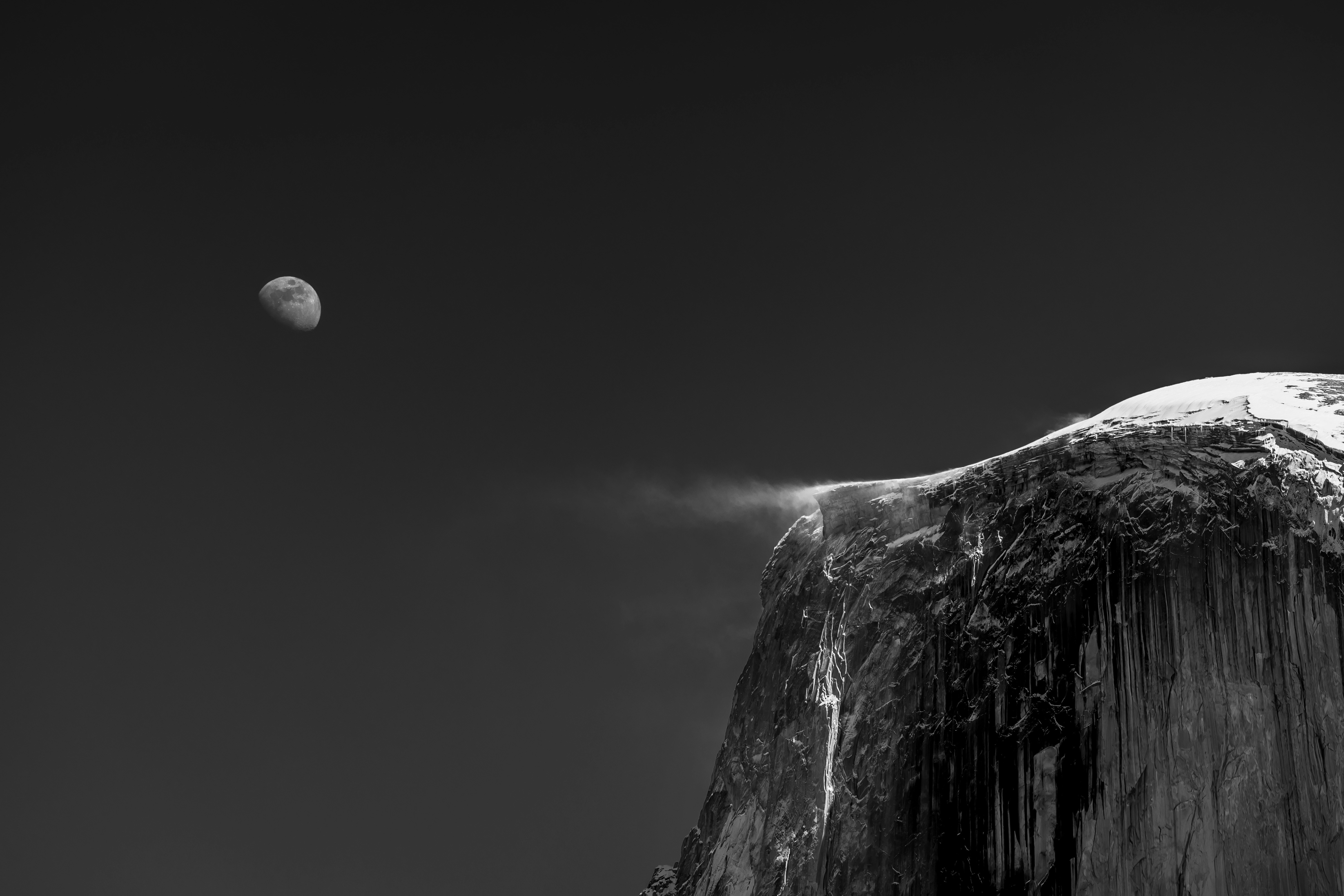 a half moon is seen over the top of a mountain