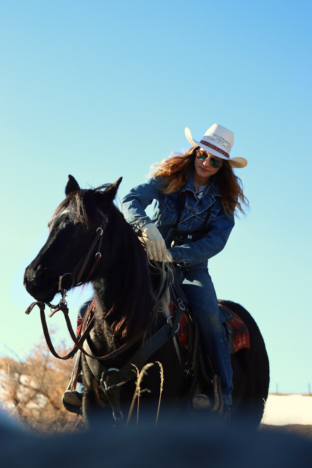 uma mulher em um chapéu de cowboy montado em um cavalo