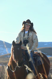 a woman riding on the back of a brown horse