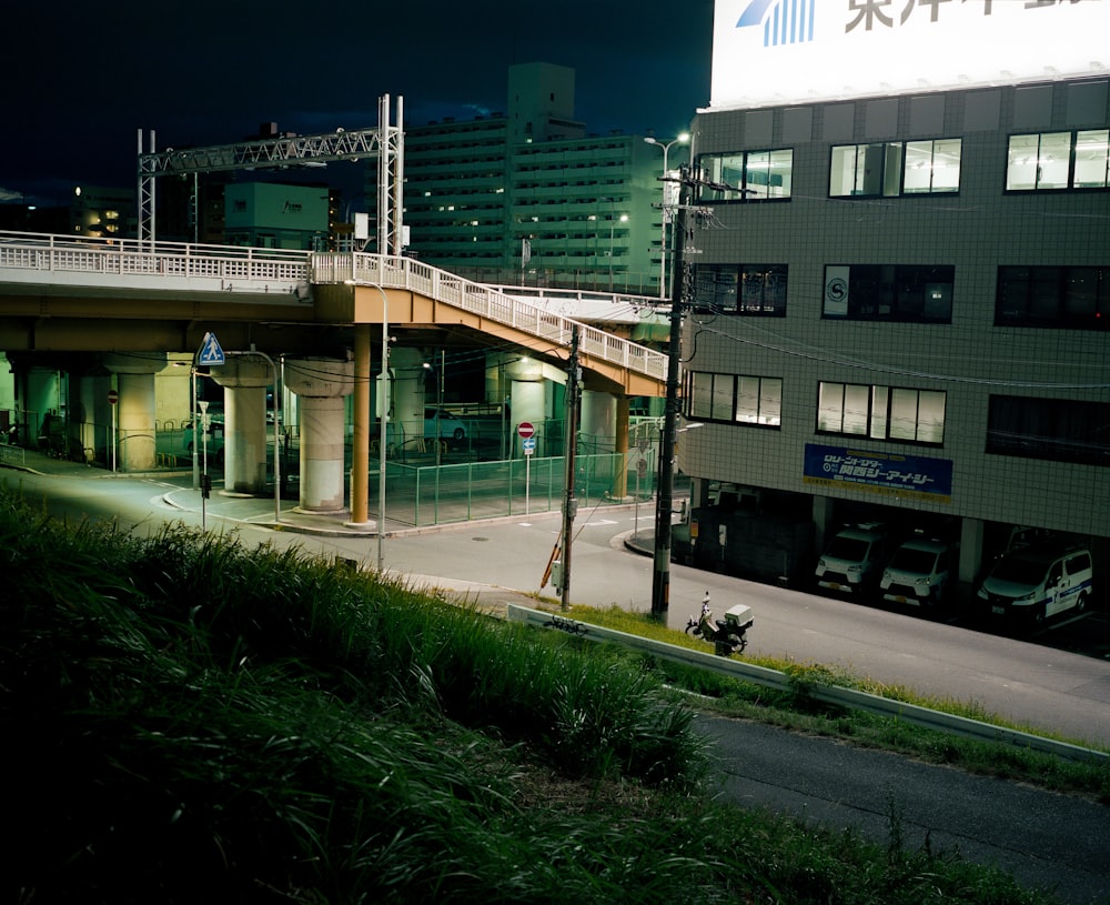 a city street at night with a bridge over it