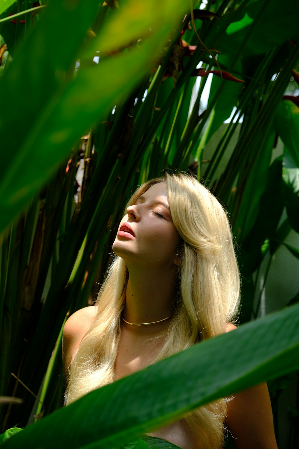 a woman with long blonde hair standing in a jungle