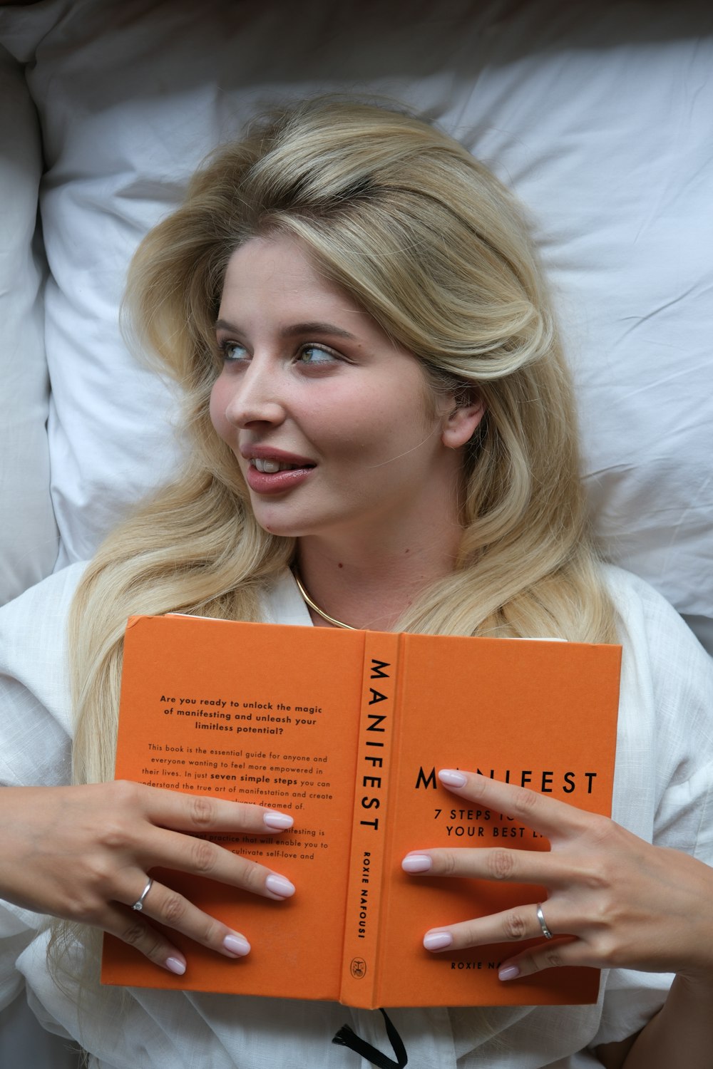 a woman laying in bed holding a book