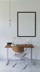 a desk with a chair and a picture hanging on the wall