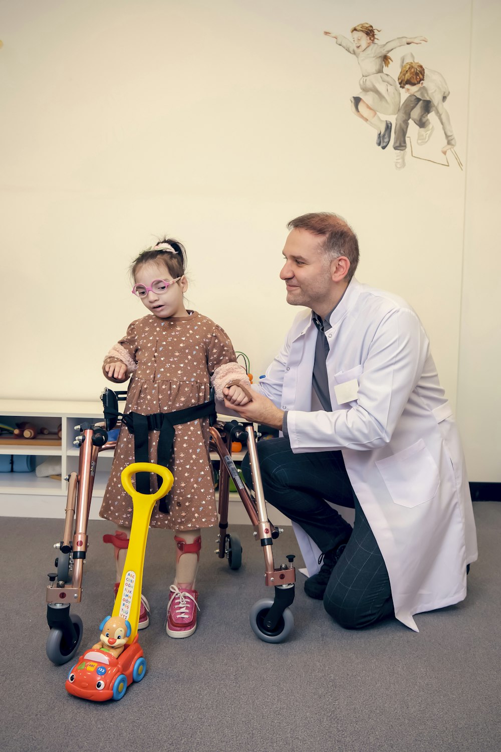 a man kneeling down next to a little girl with crutches