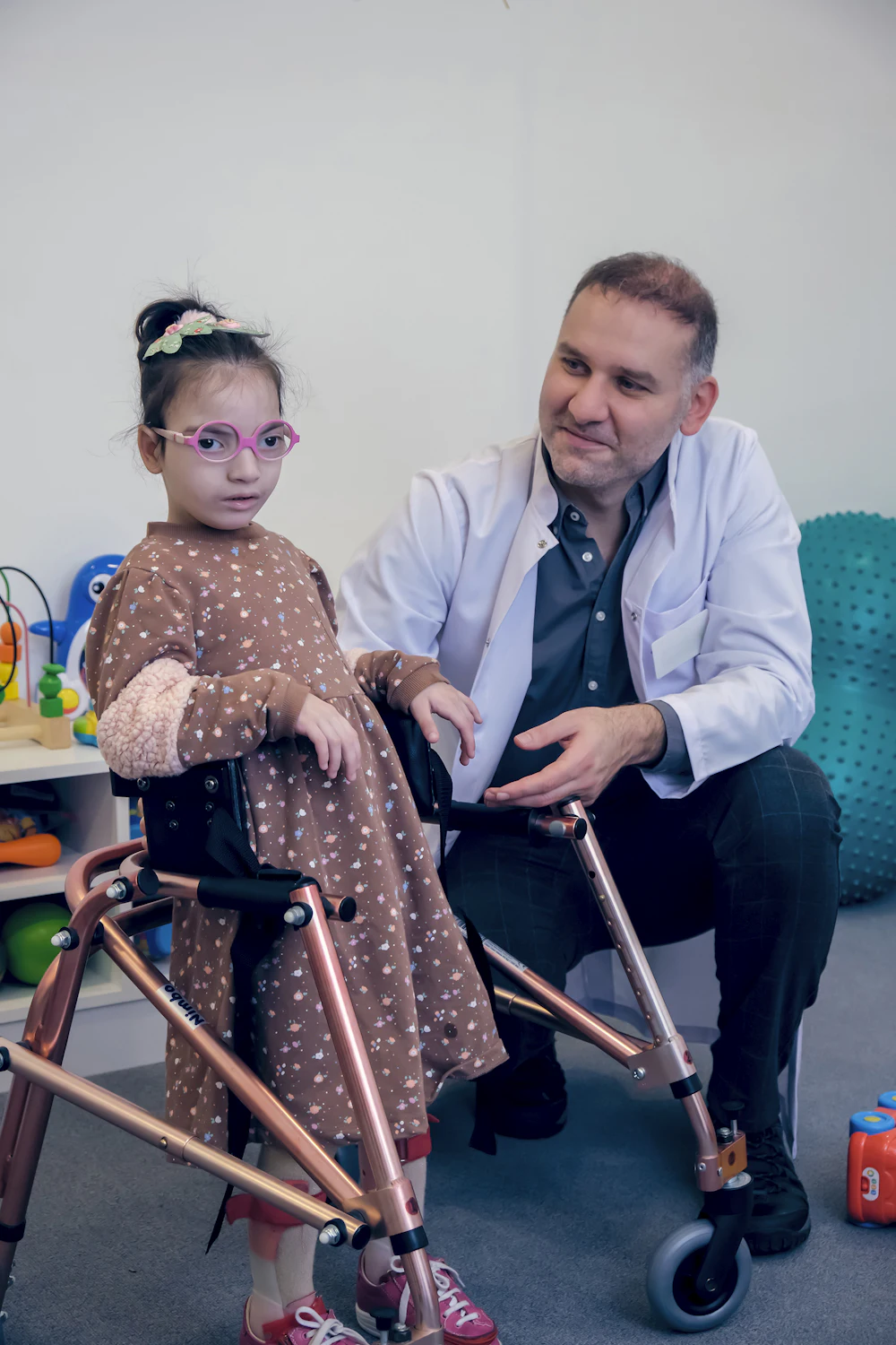 Clinician supporting a young girl using a walker