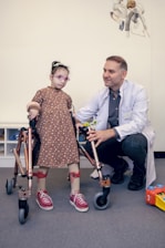 a man sitting next to a little girl with crutches