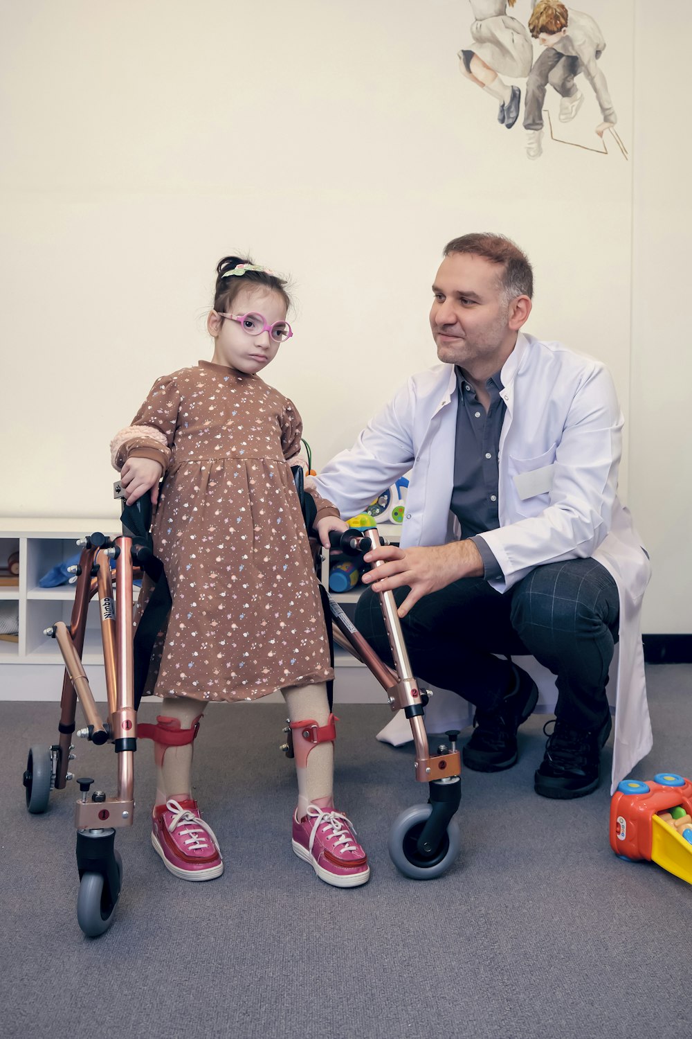 Ein Mann sitzt neben einem kleinen Mädchen mit Krücken