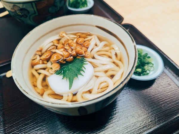 A bowl of noodles with peanuts and sour cream