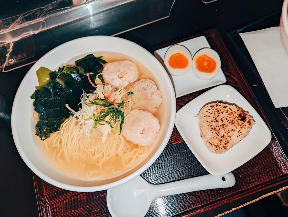 a bowl of ramen with a side of eggs