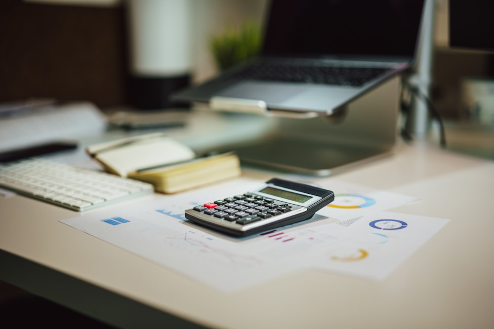 une calculatrice posée sur une table à côté d’un ordinateur portable