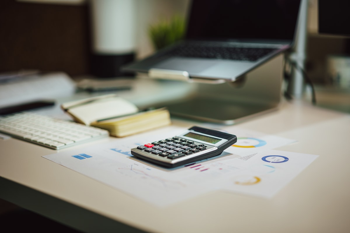 Rekenmachine en laptop op een bureau — MKB-ondernemer berekent het marketingbudget