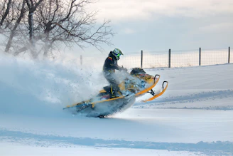 a man riding a snowmobile down a snow covered slope