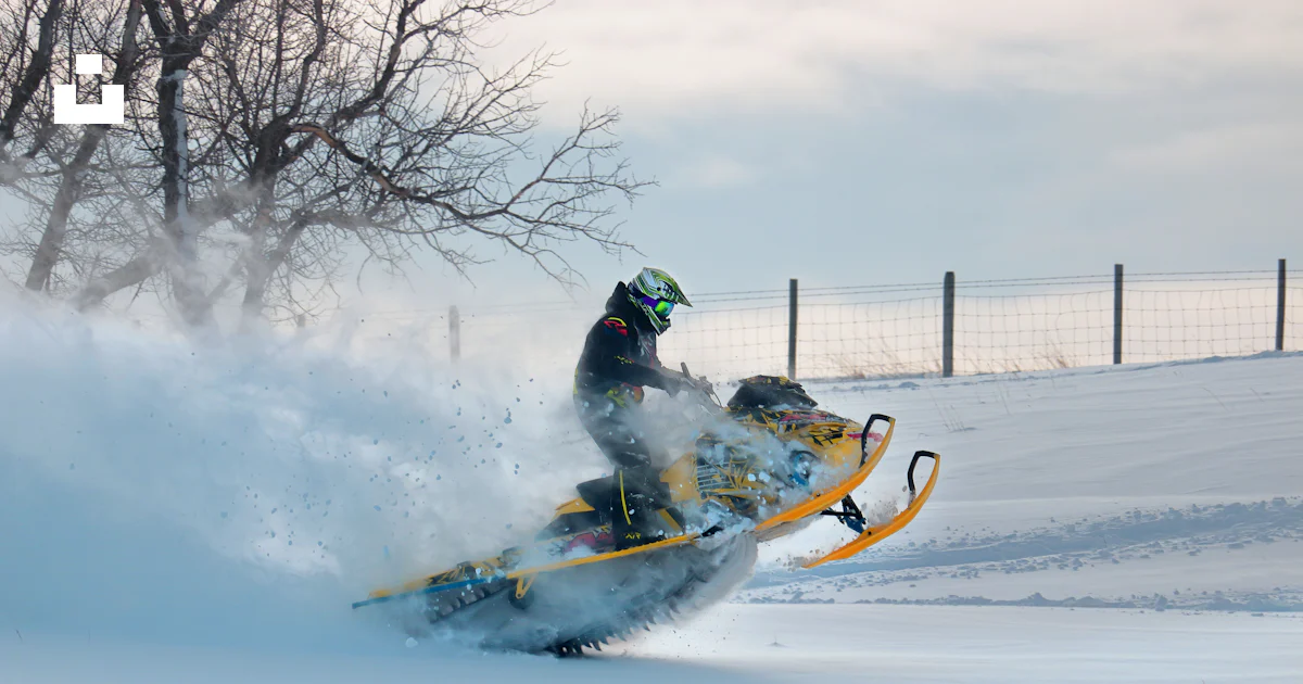 A man riding a snowmobile down a snow covered slope photo – Free Man ...