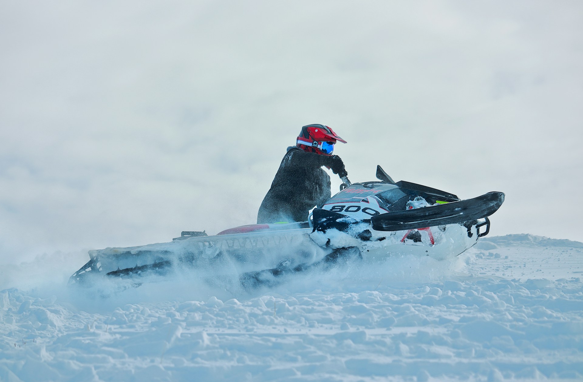 a man riding a snowmobile down a snow covered slope