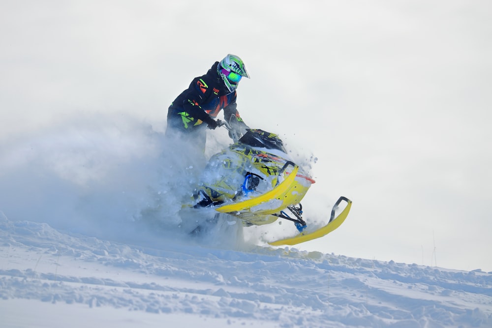 a man riding a snowmobile down a snow covered slope