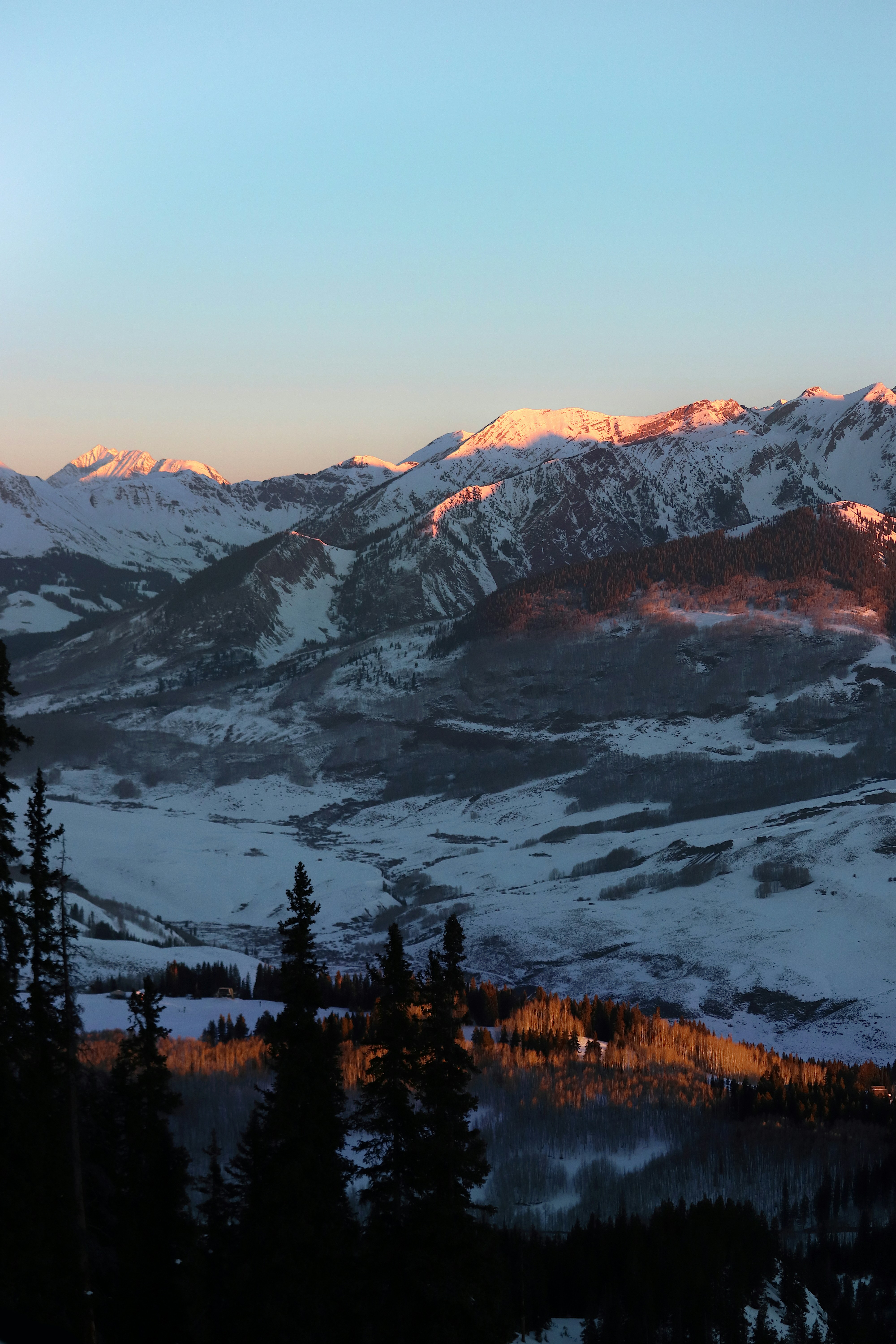 a view of a snowy mountain range at sunset