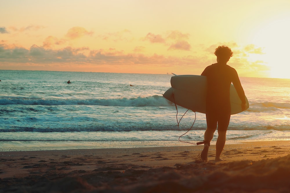 a person standing on a beach holding a surfboard