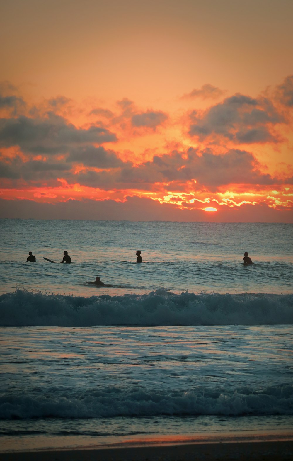Un grupo de personas montando tablas de surf en la parte superior de una ola