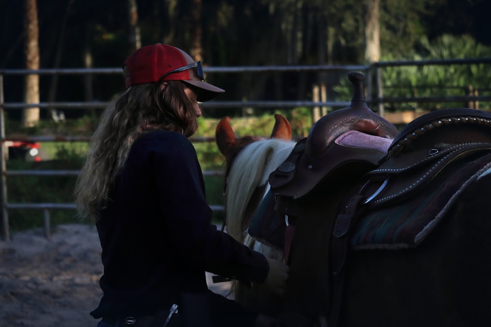 a woman standing next to a horse in a fenced in area