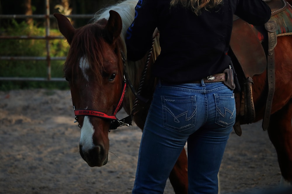 a woman in a black shirt is standing next to a brown and white horse