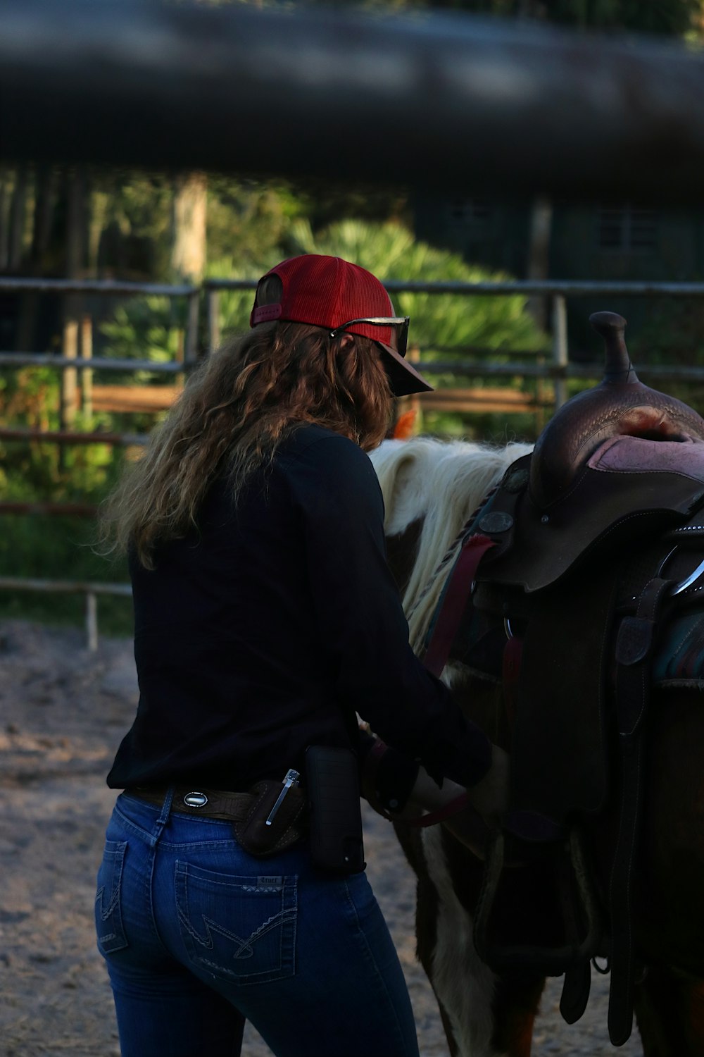 a woman wearing a red hat standing next to a horse