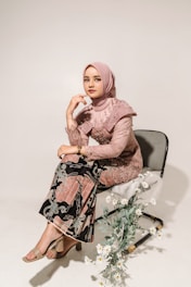 a woman sitting on a chair next to a vase of flowers