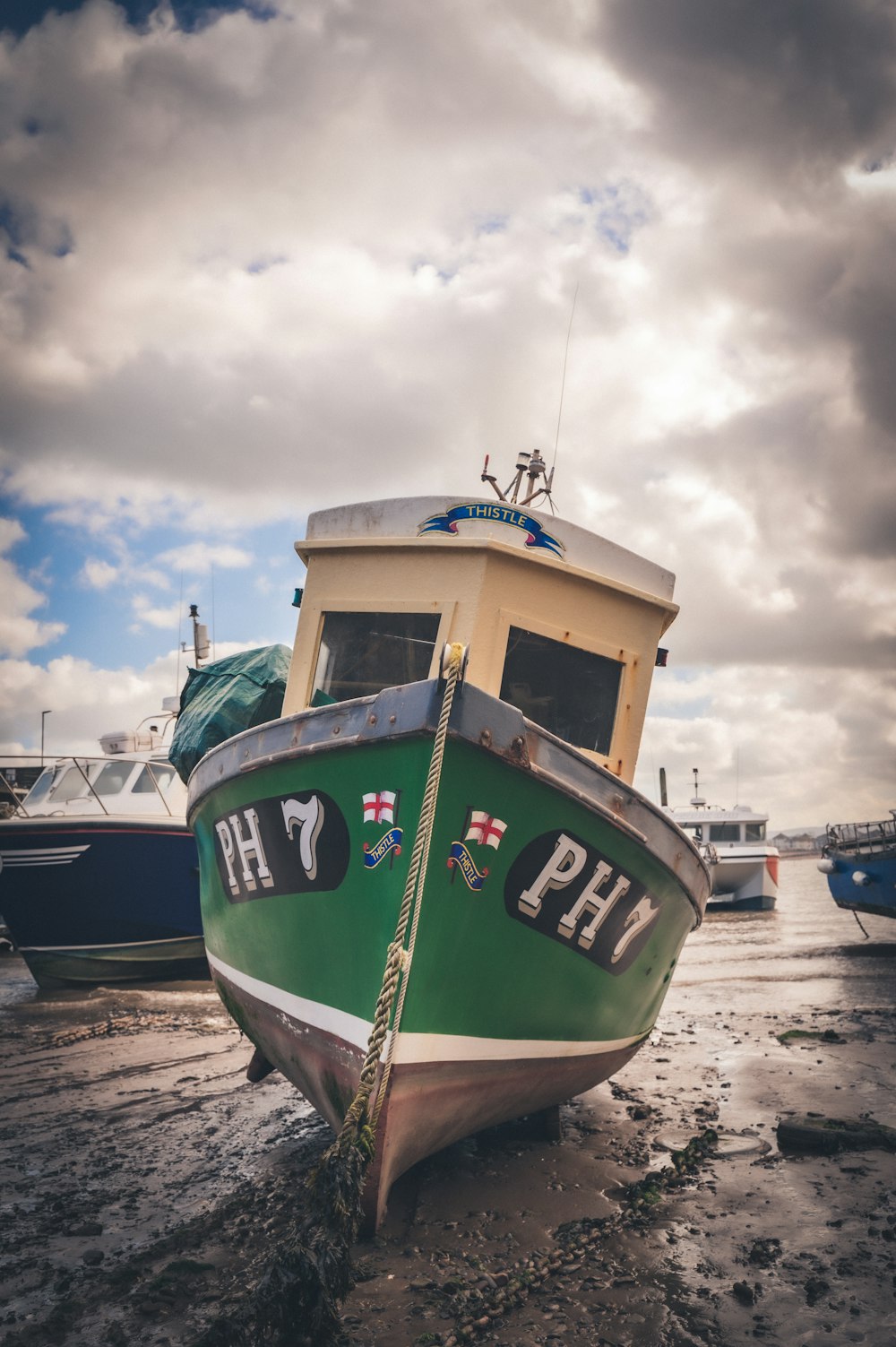 a green and white boat sitting on top of a beach