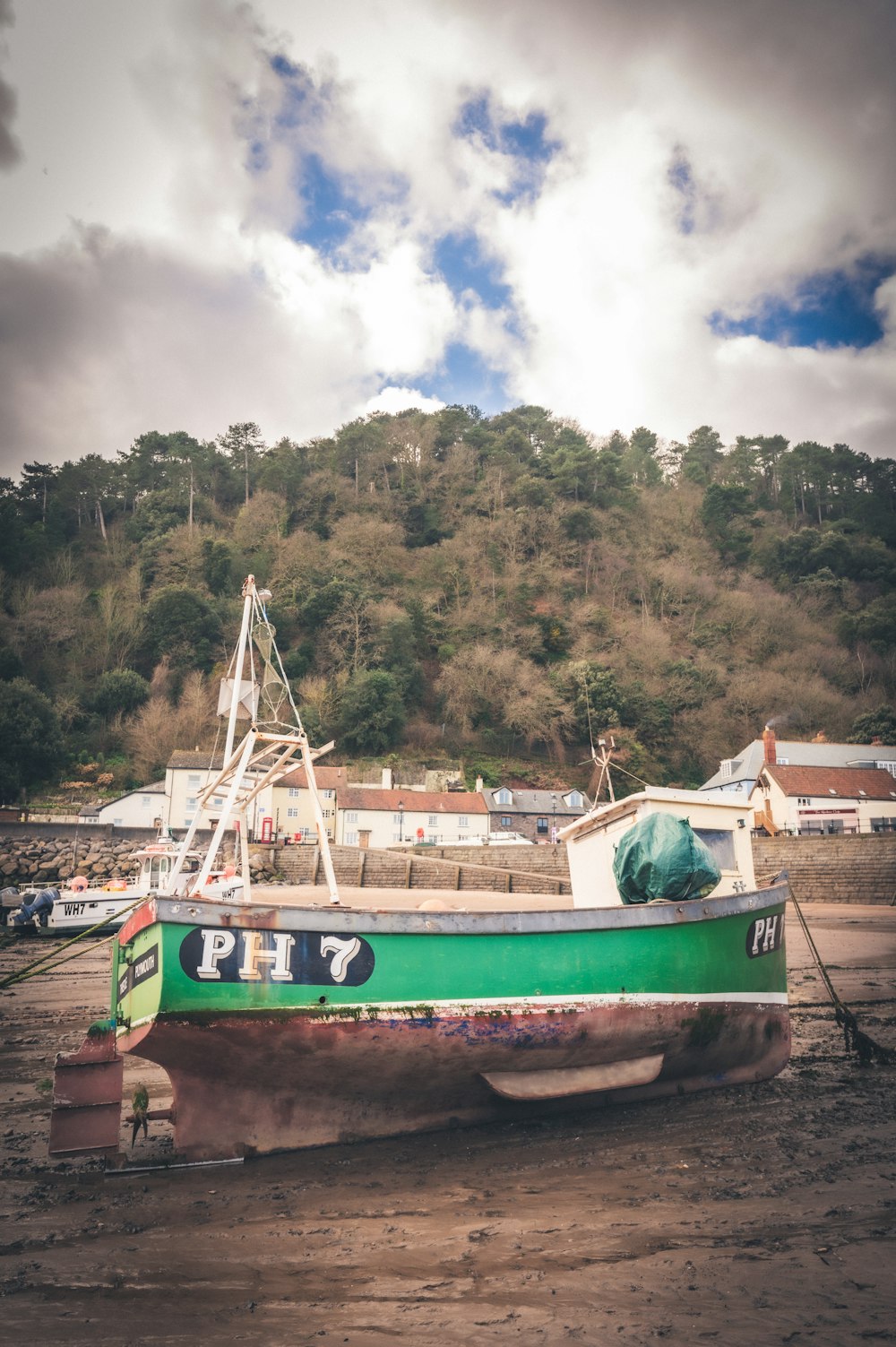 a green boat sitting on top of a sandy beach