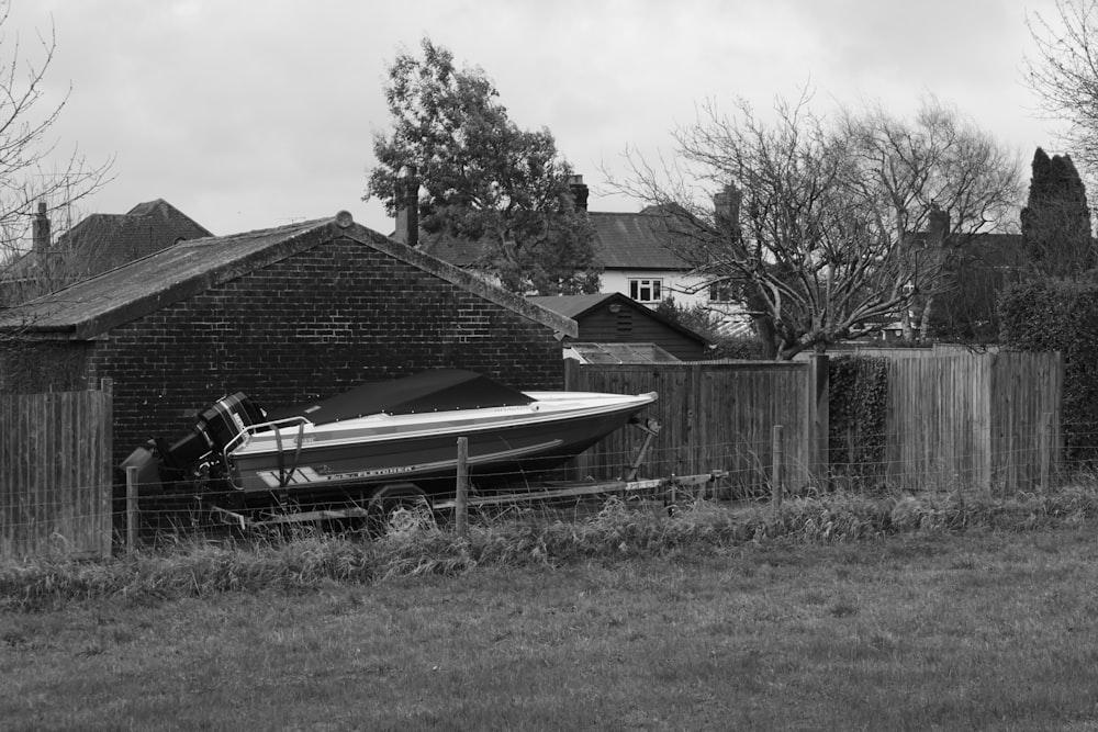 a boat sitting in the grass next to a fence