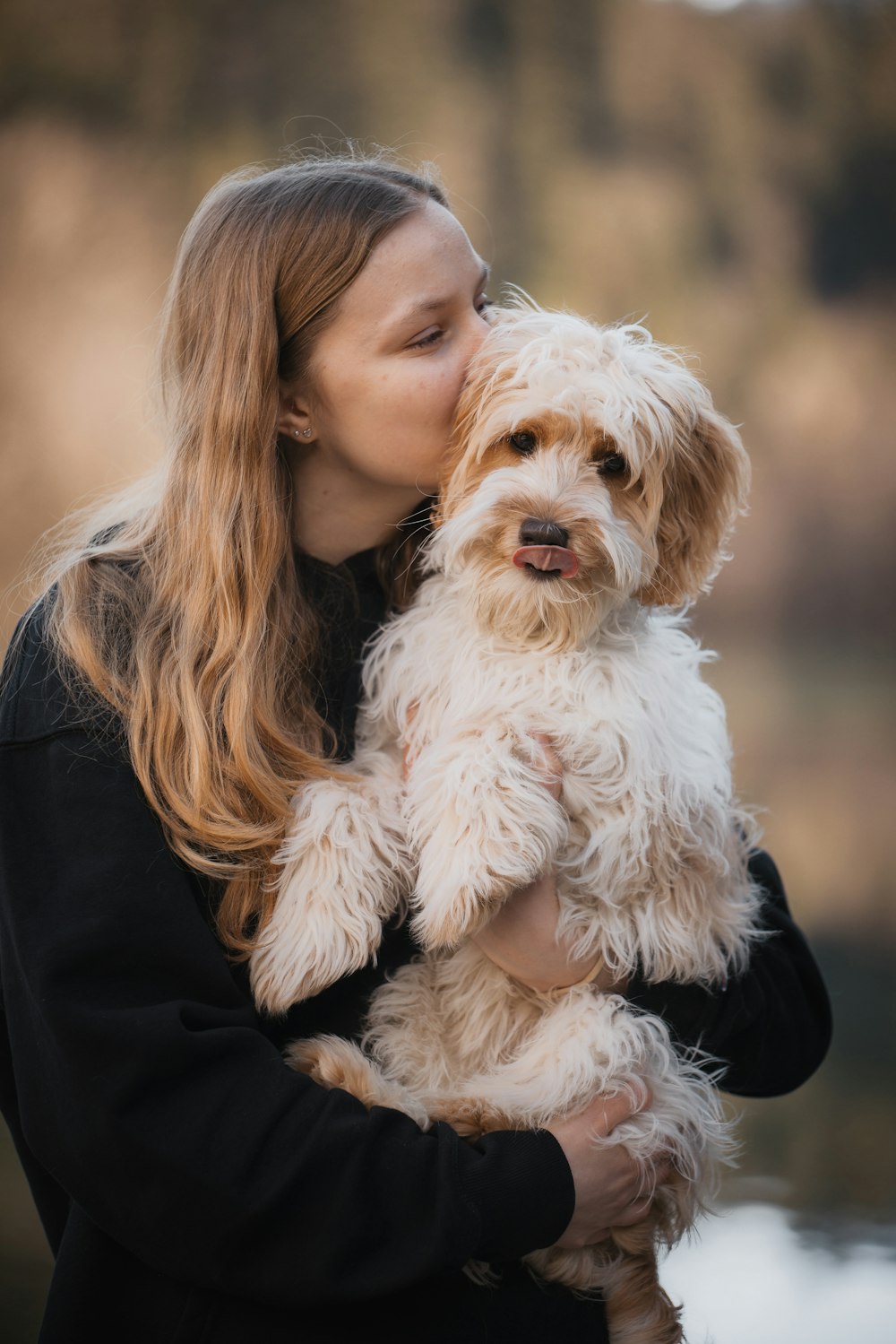 uma mulher segurando um cão branco em seus braços