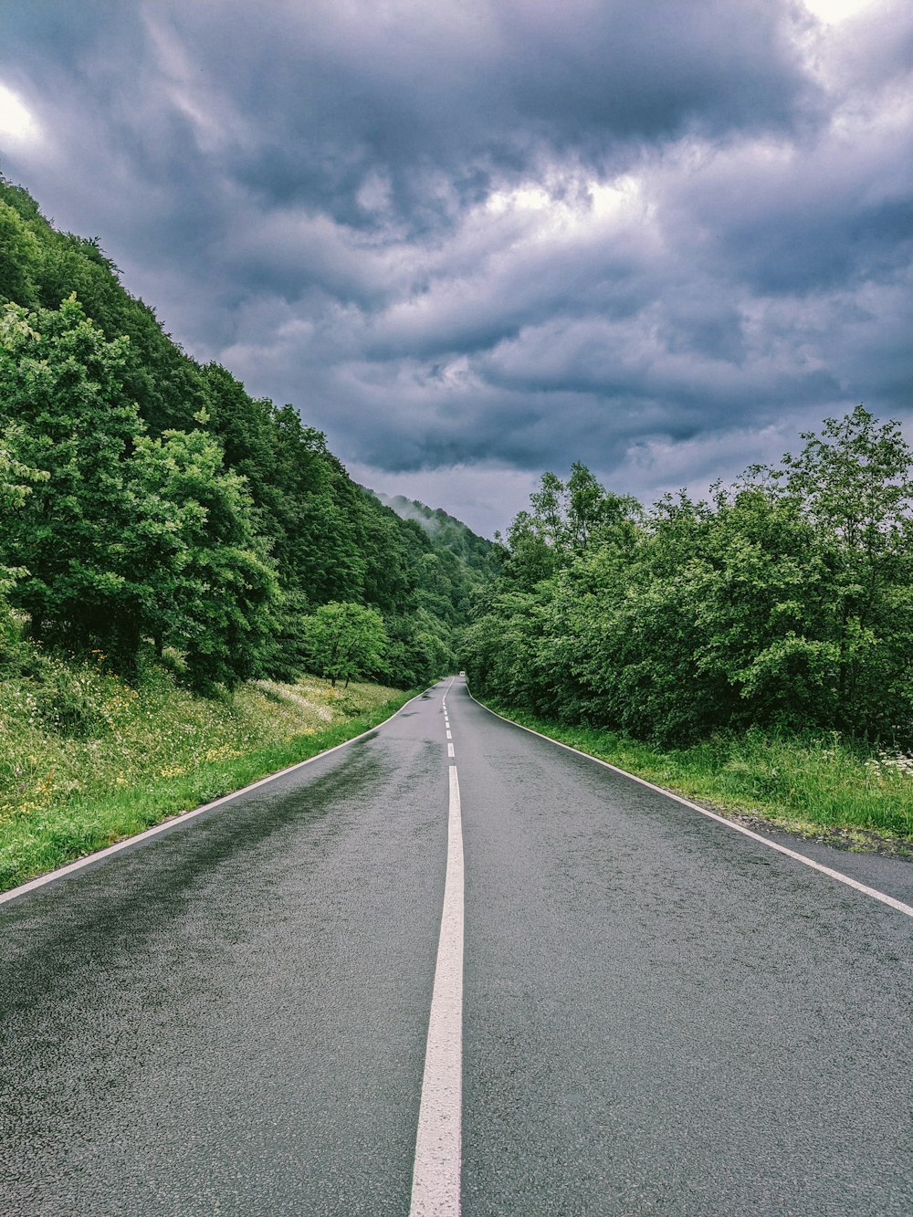 an empty road with a cloudy sky in the background