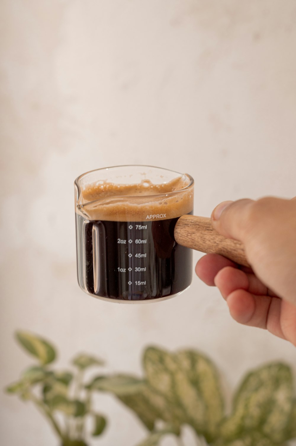 a person holding a glass of beer with a wooden stick