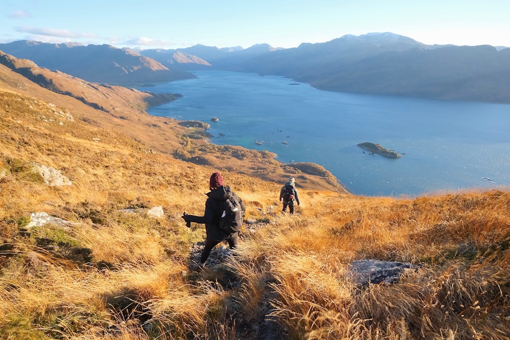 a couple of people hiking up a hill