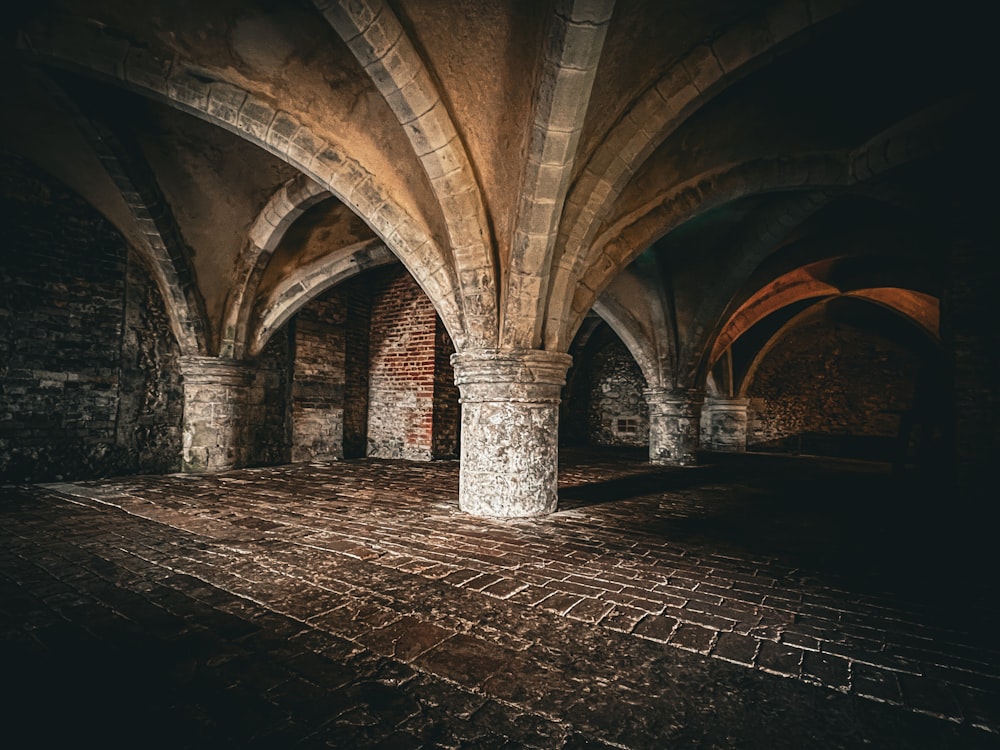 uma sala mal iluminada com pisos de tijolos e arcos