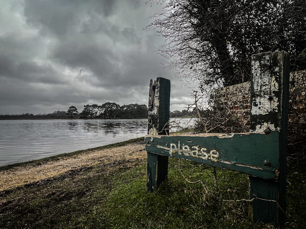 a wooden sign sitting on the side of a lush green field