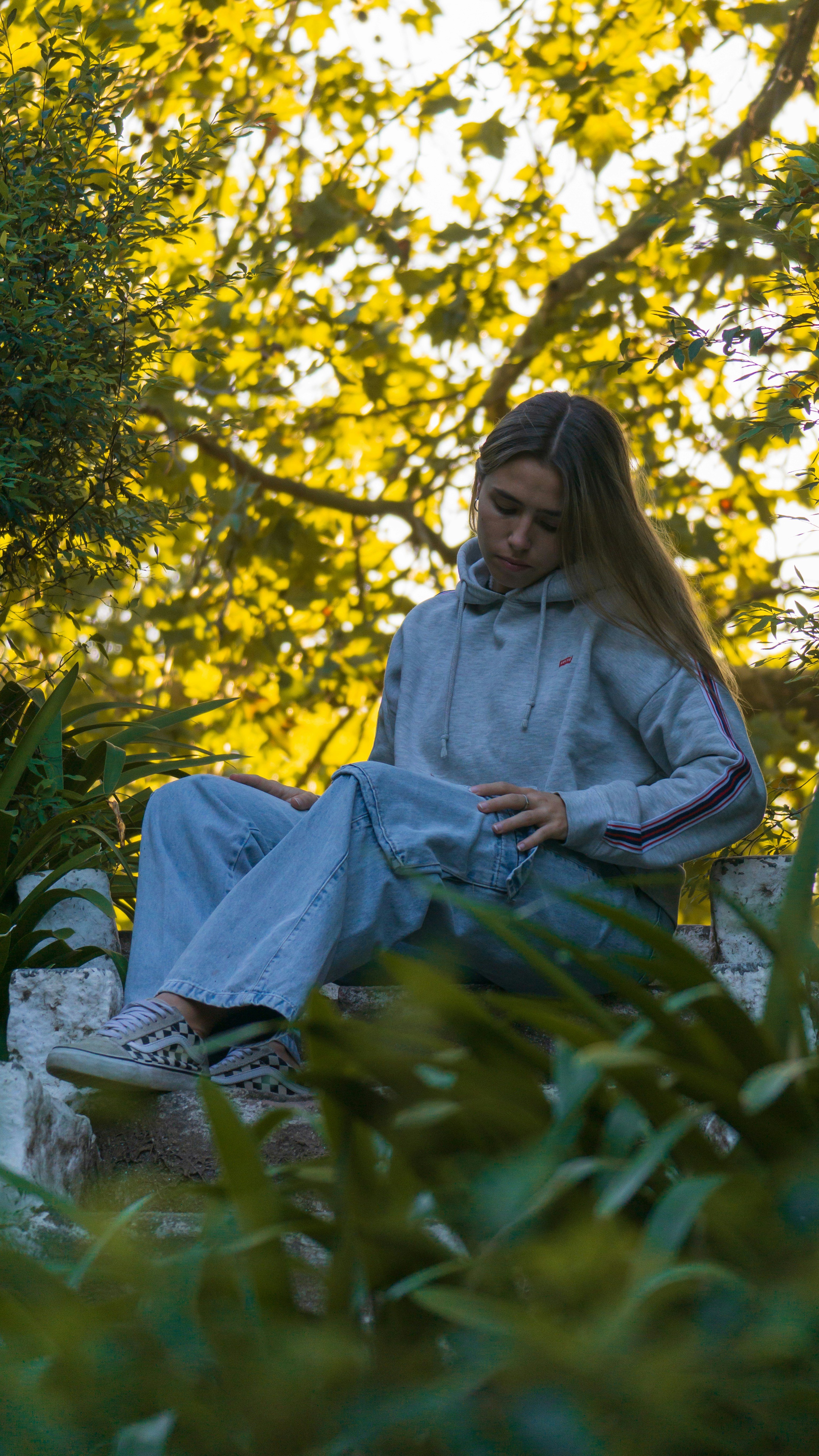a woman sitting on top of a rock next to a tree