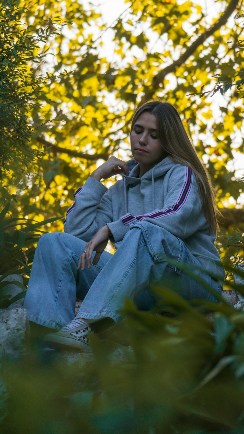 a woman sitting on a rock in front of a tree