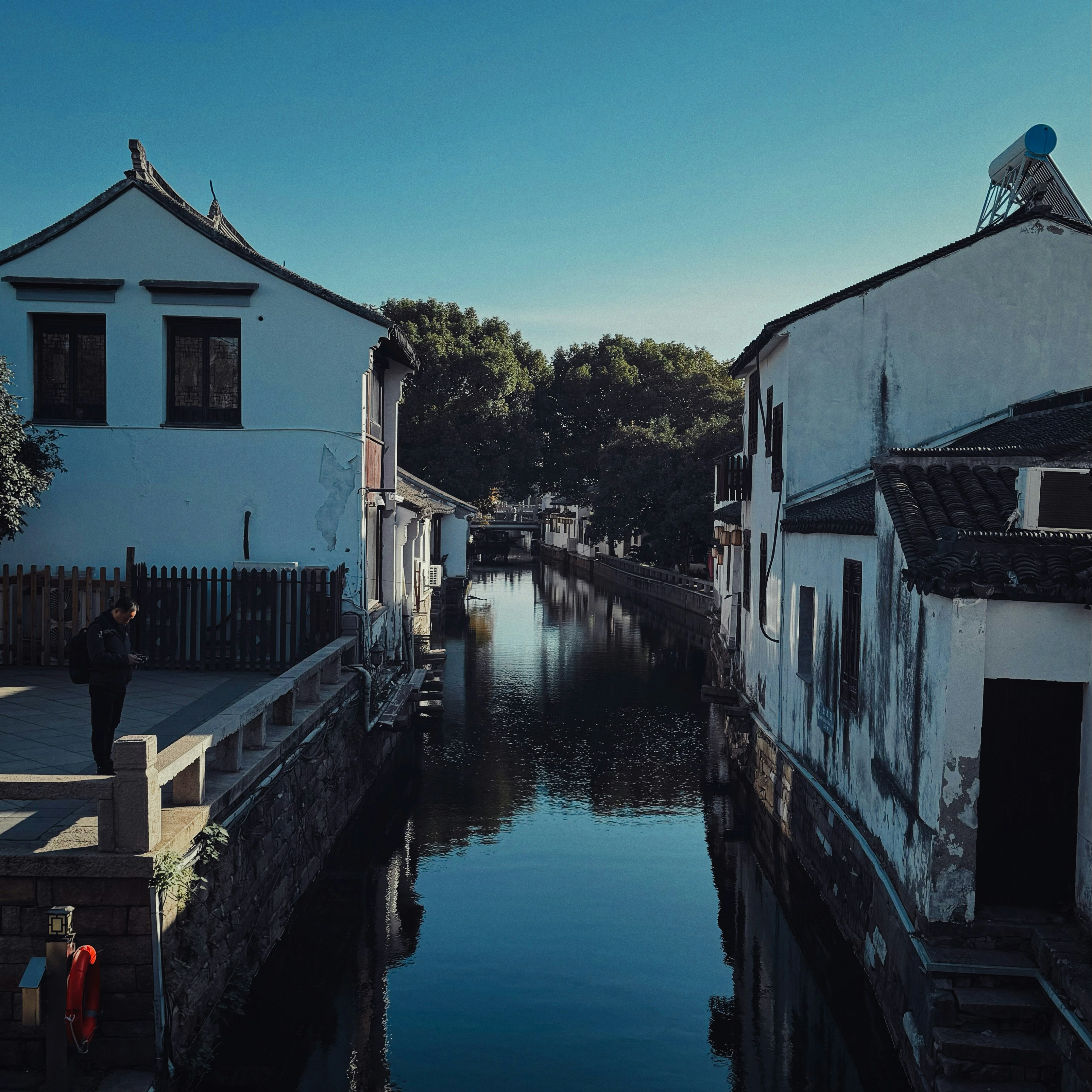 eine Person, die auf einer Brücke über ein Gewässer steht