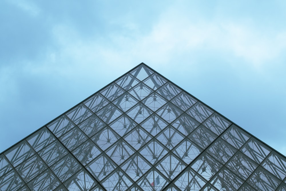 a very tall glass pyramid with a sky background