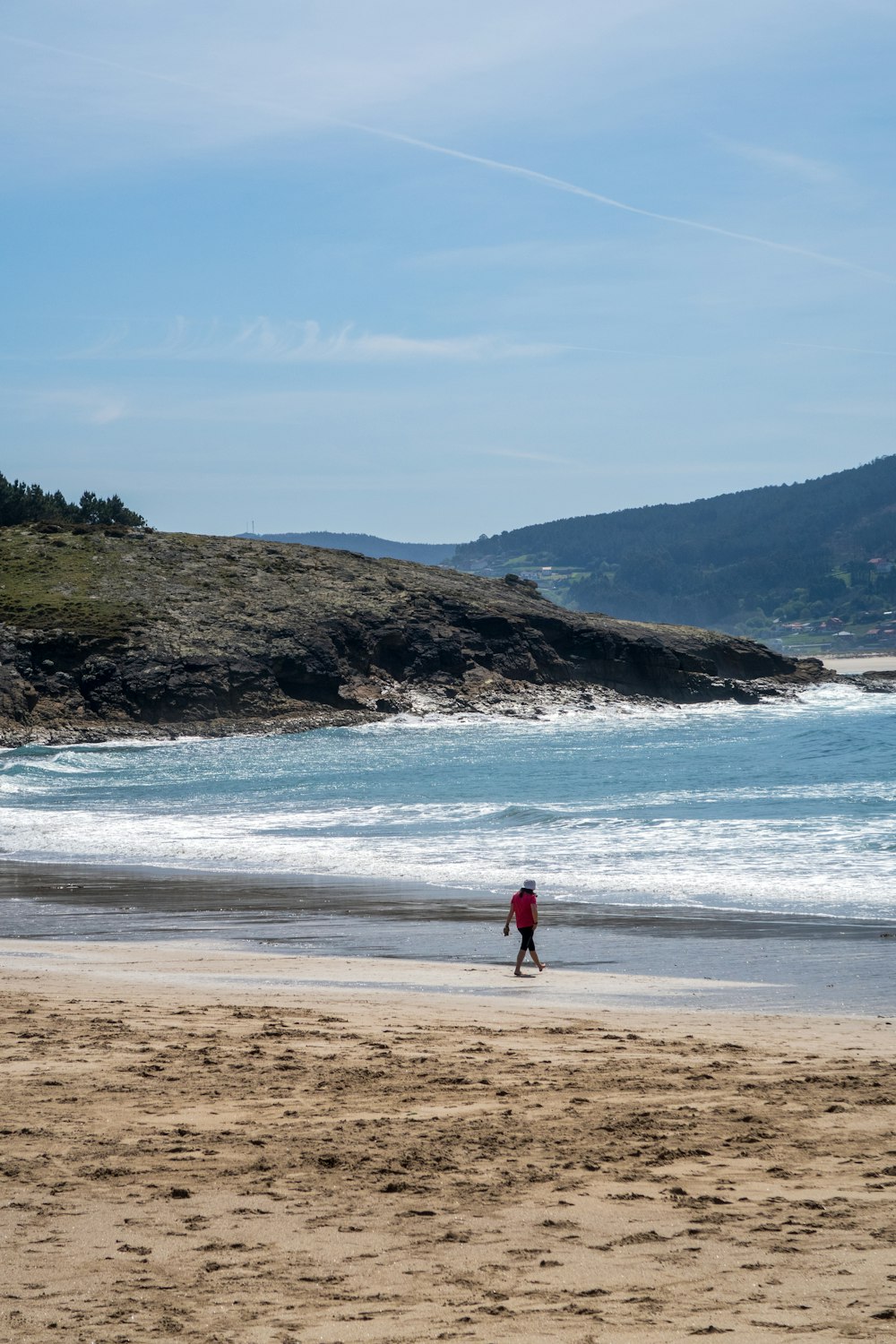 a person walking on a beach next to the ocean